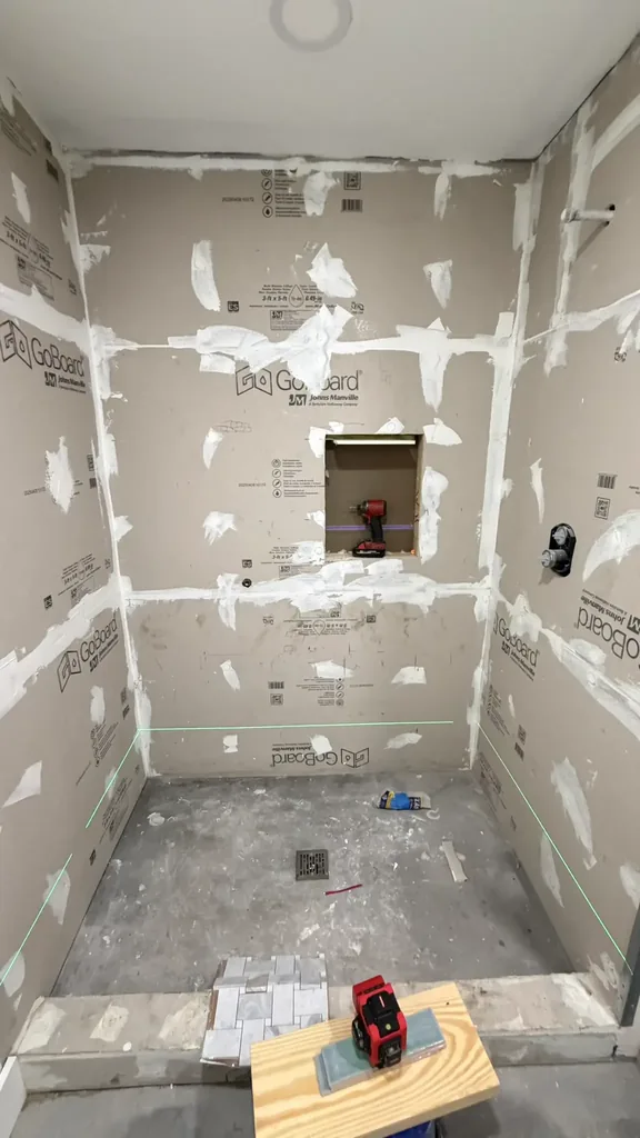 Shower before tile installation with backer-board walls, treated joints, recessed niche opening and laser line