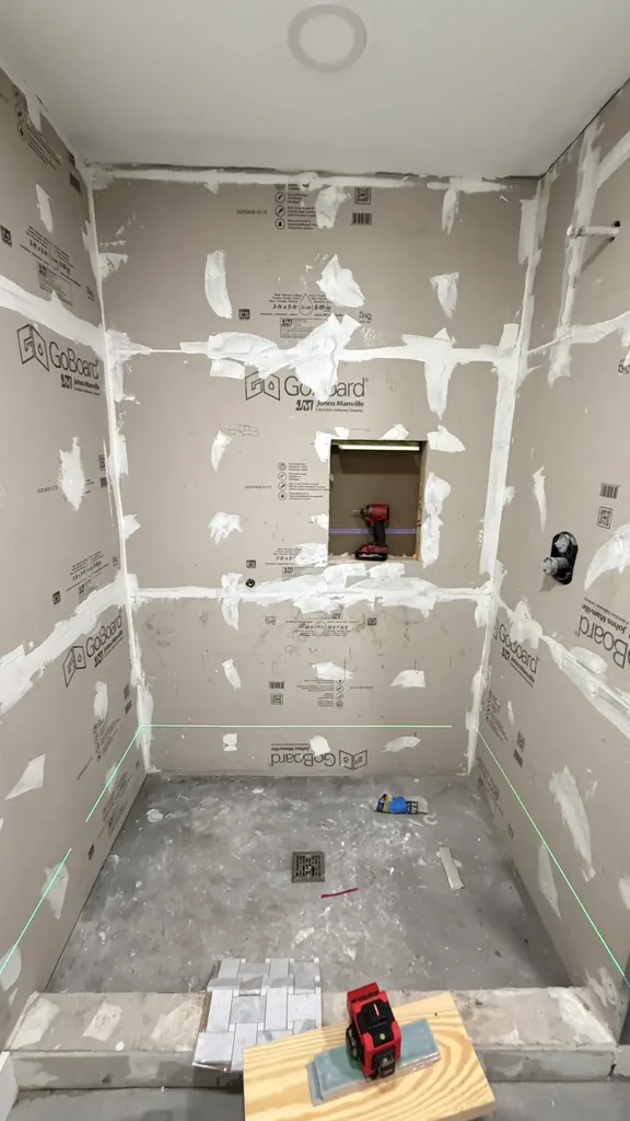 Second view of the shower preparation stage with uncovered base, central drain and backer-board walls
